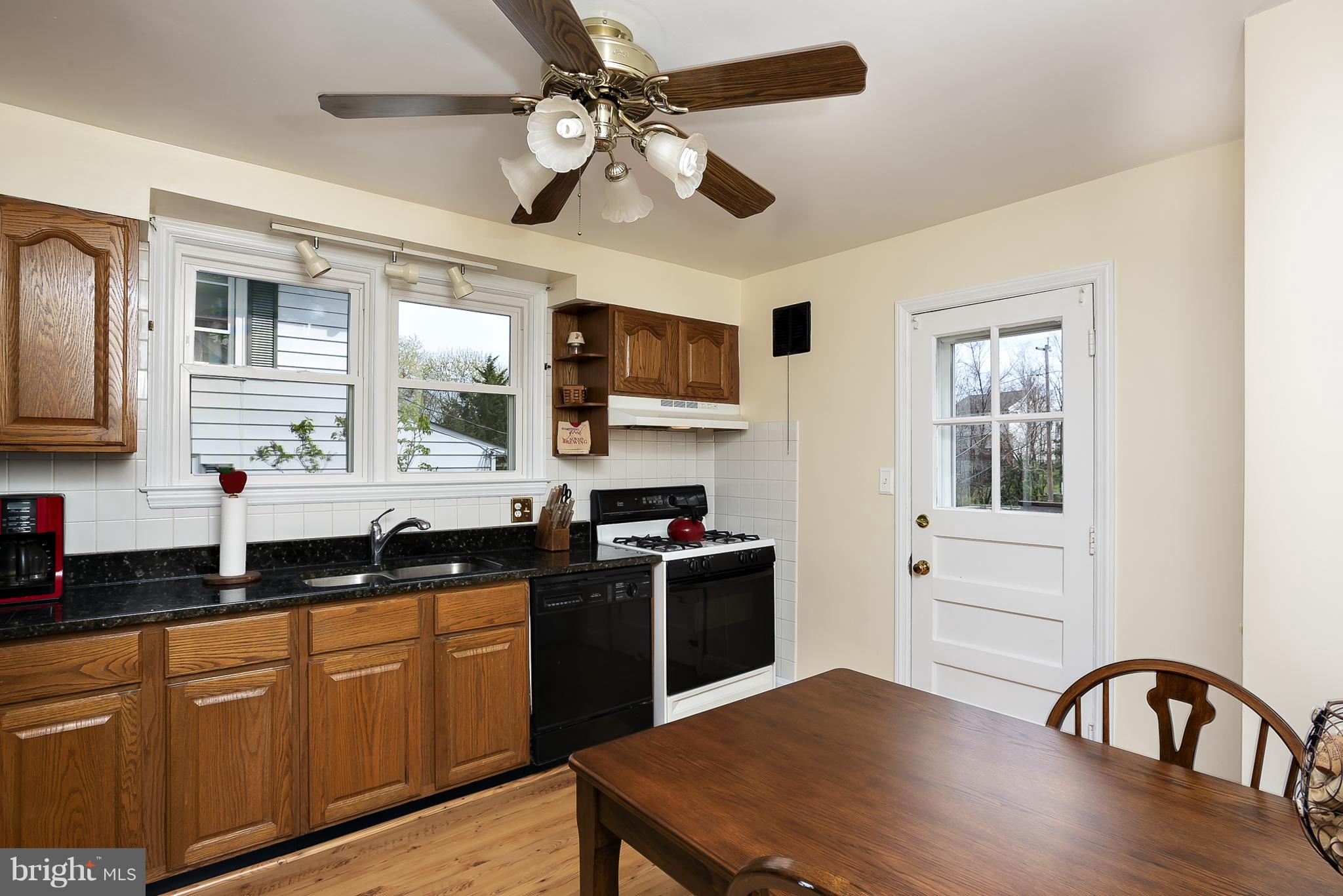 618 Coleraine Road Baltimore, MD 21229 - Photo 8 of 27 a kitchen with stainless steel appliances granite countertop a stove top oven a sink dishwasher a dining table and chairs with wooden floor