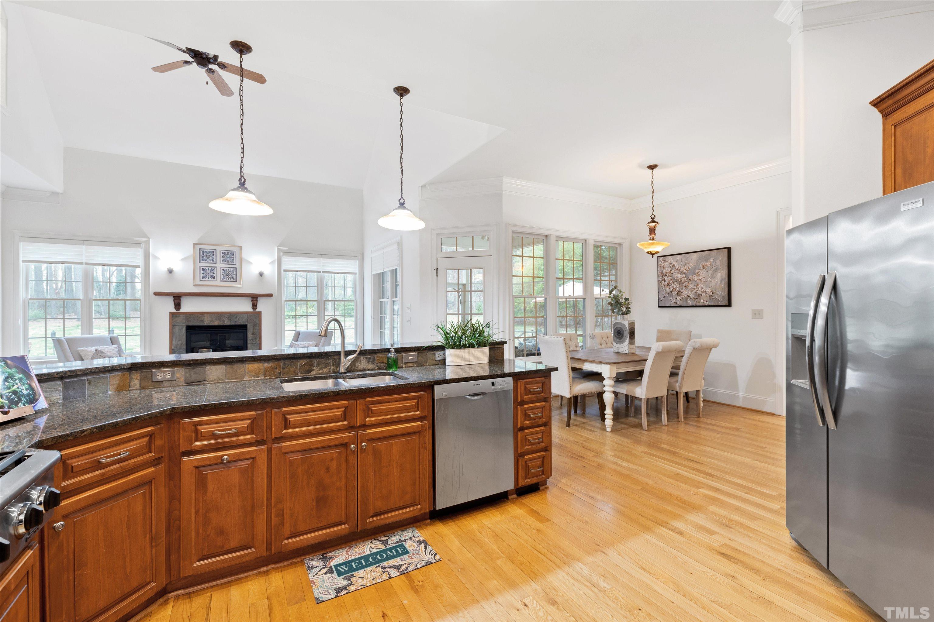 1904 Bowling Green Trail Raleigh, NC 27613 - Photo 14 of 43 a large kitchen with stainless steel appliances granite countertop a stove back oven a sink dishwasher a dining table and chairs with wooden floor