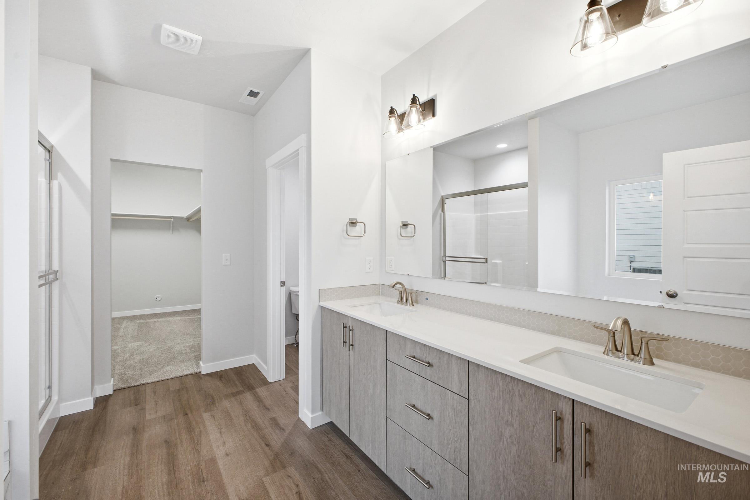 5293 South Memory Avenue Meridian, ID 83642 - Photo 21 of 24 Full bath featuring a shower stall, double vanity, a walk in closet, and dark wood-type flooring
