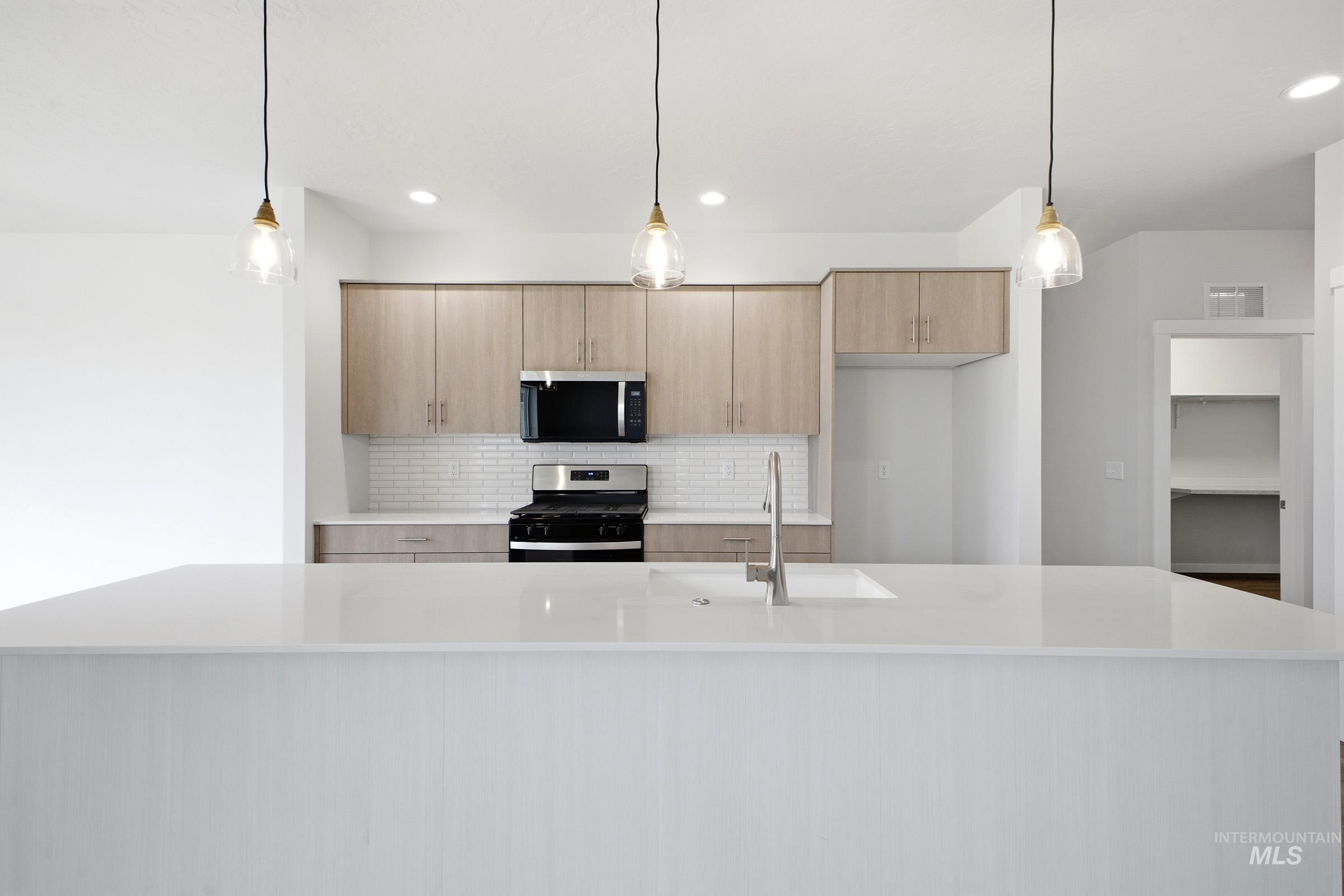 5293 South Memory Avenue Meridian, ID 83642 - Photo 5 of 24 Kitchen with light wood finish cabinetry, pendant lighting, stainless steel appliances, and a large island