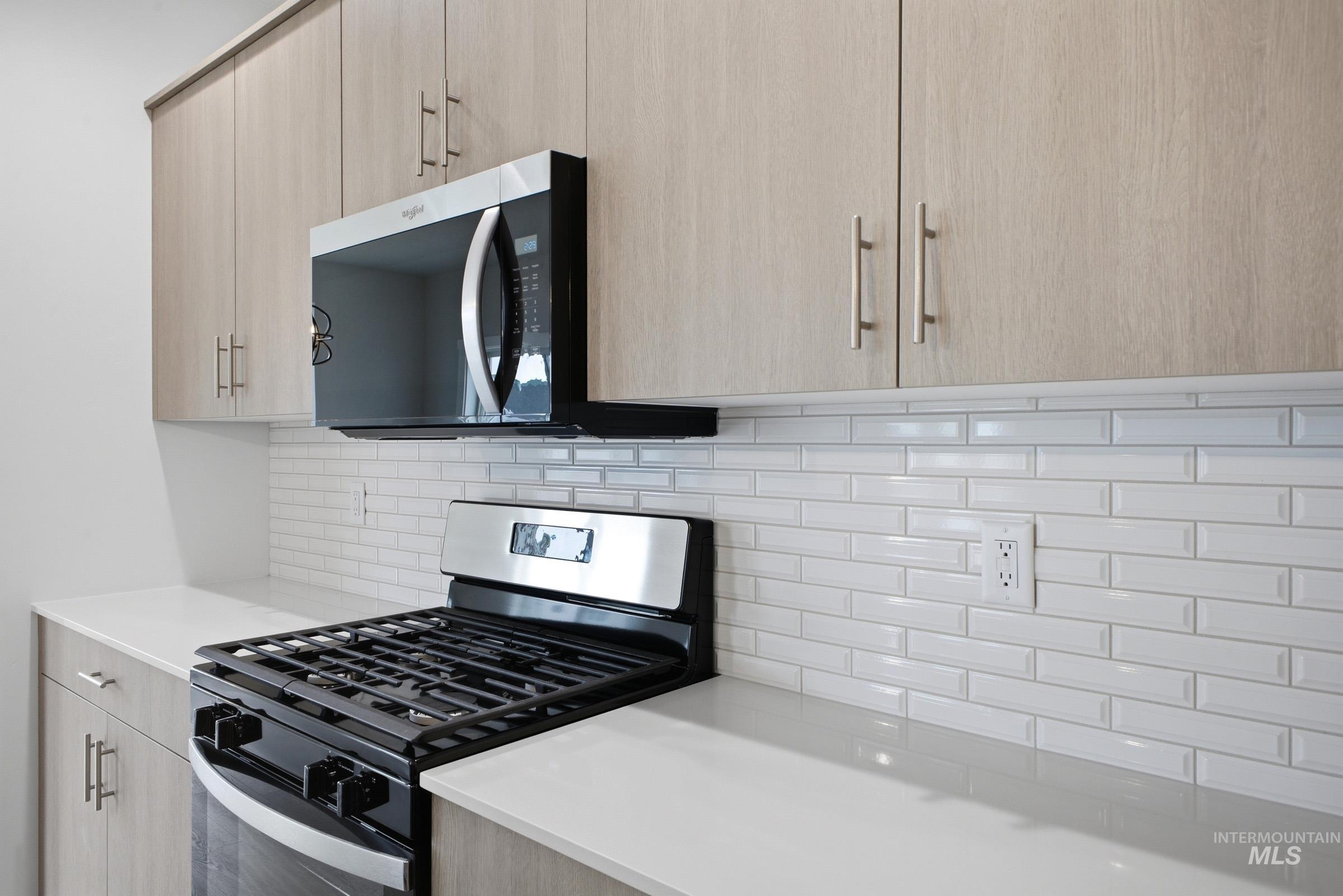 5293 South Memory Avenue Meridian, ID 83642 - Photo 7 of 24 Kitchen featuring stainless steel appliances, light wood finish cabinets, modern cabinets, tasteful backsplash, and light stone countertops