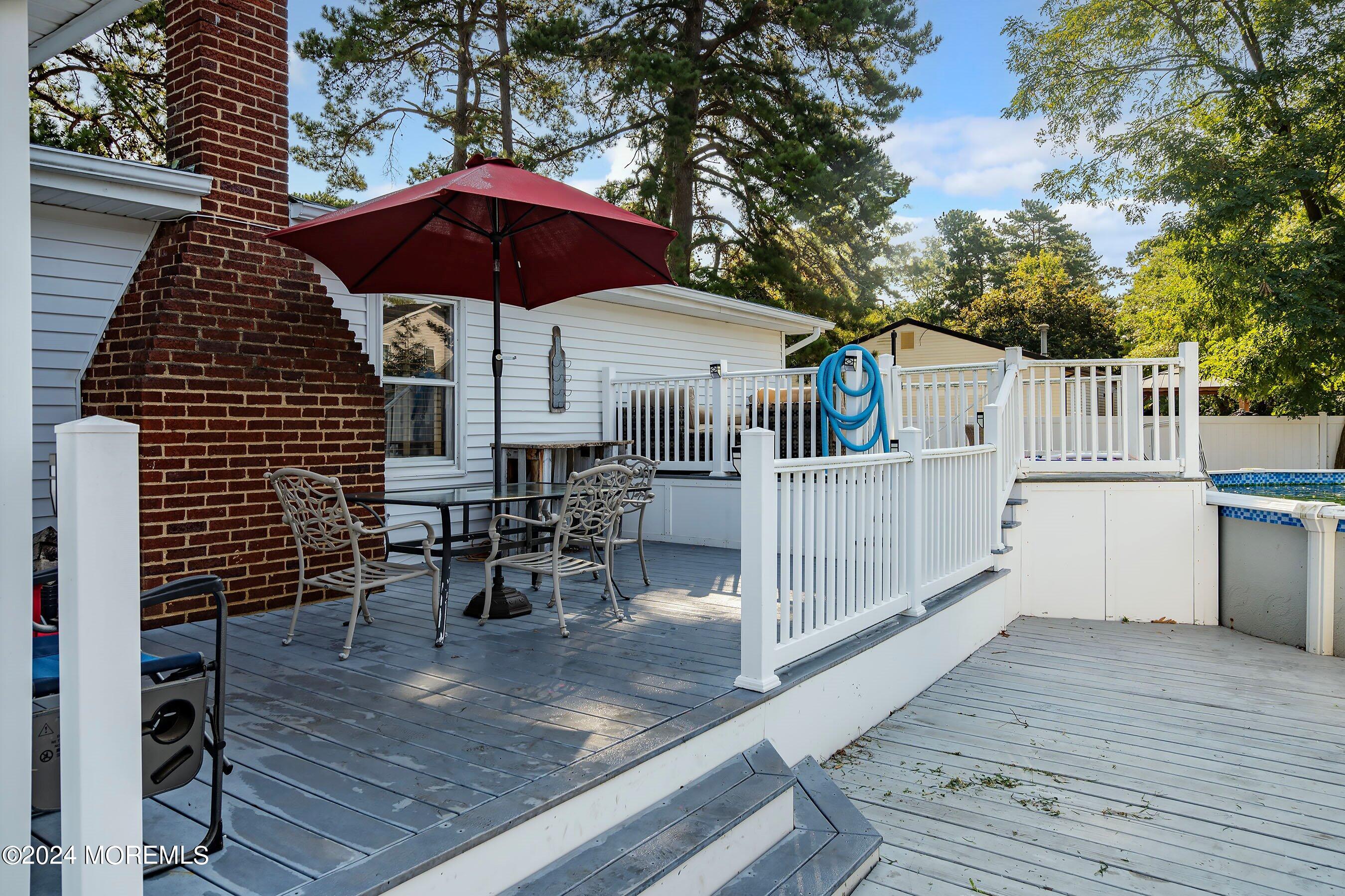 1507 Whitcomb Road Forked River, NJ 08731 - Photo 18 of 30 a view of a roof deck with table and chairs under an umbrella with wooden floor