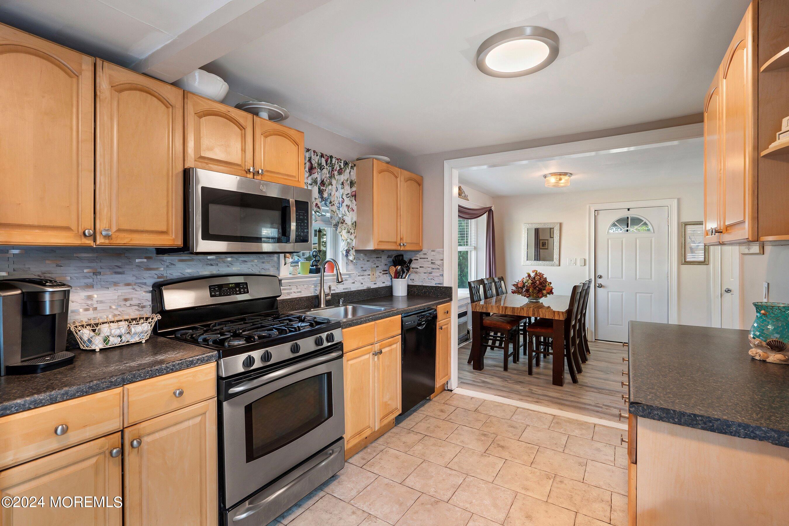1507 Whitcomb Road Forked River, NJ 08731 - Photo 8 of 30 a kitchen with stainless steel appliances granite countertop a stove top oven a sink a dining table and chairs with wooden floor