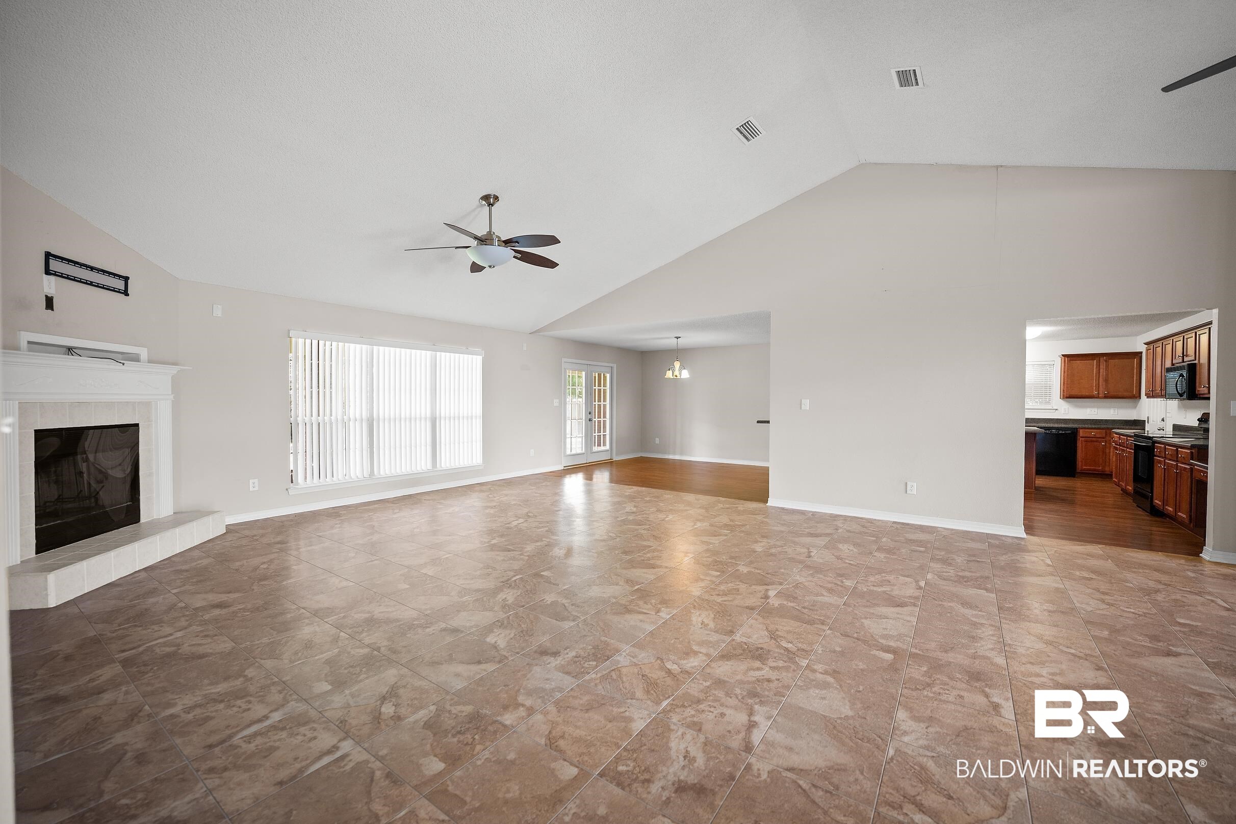 323 Manchester Lane Foley, AL 36535 - Photo 7 of 30 Spacious living area featuring vaulted ceilings, light-toned tiled flooring, and a white mantle fireplace with a hearth