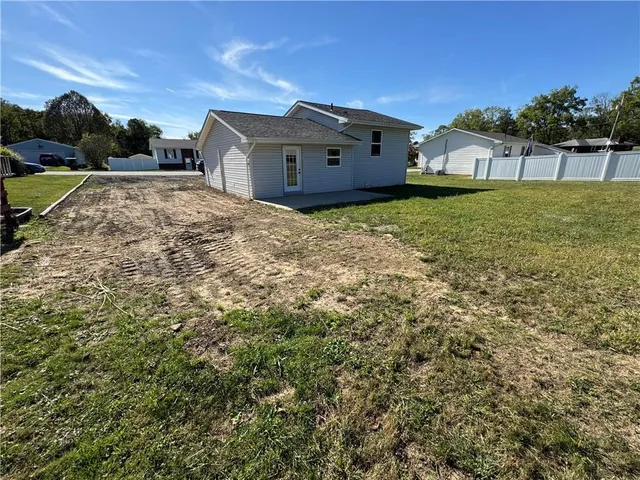 a view of a house with a big yard and large tree