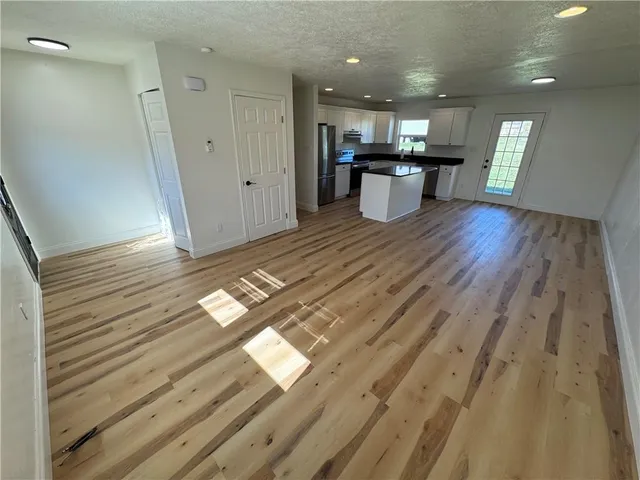 a view of a kitchen with kitchen island wooden floor and stainless steel appliances