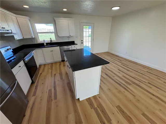 a kitchen with granite countertop a sink a stove and cabinets