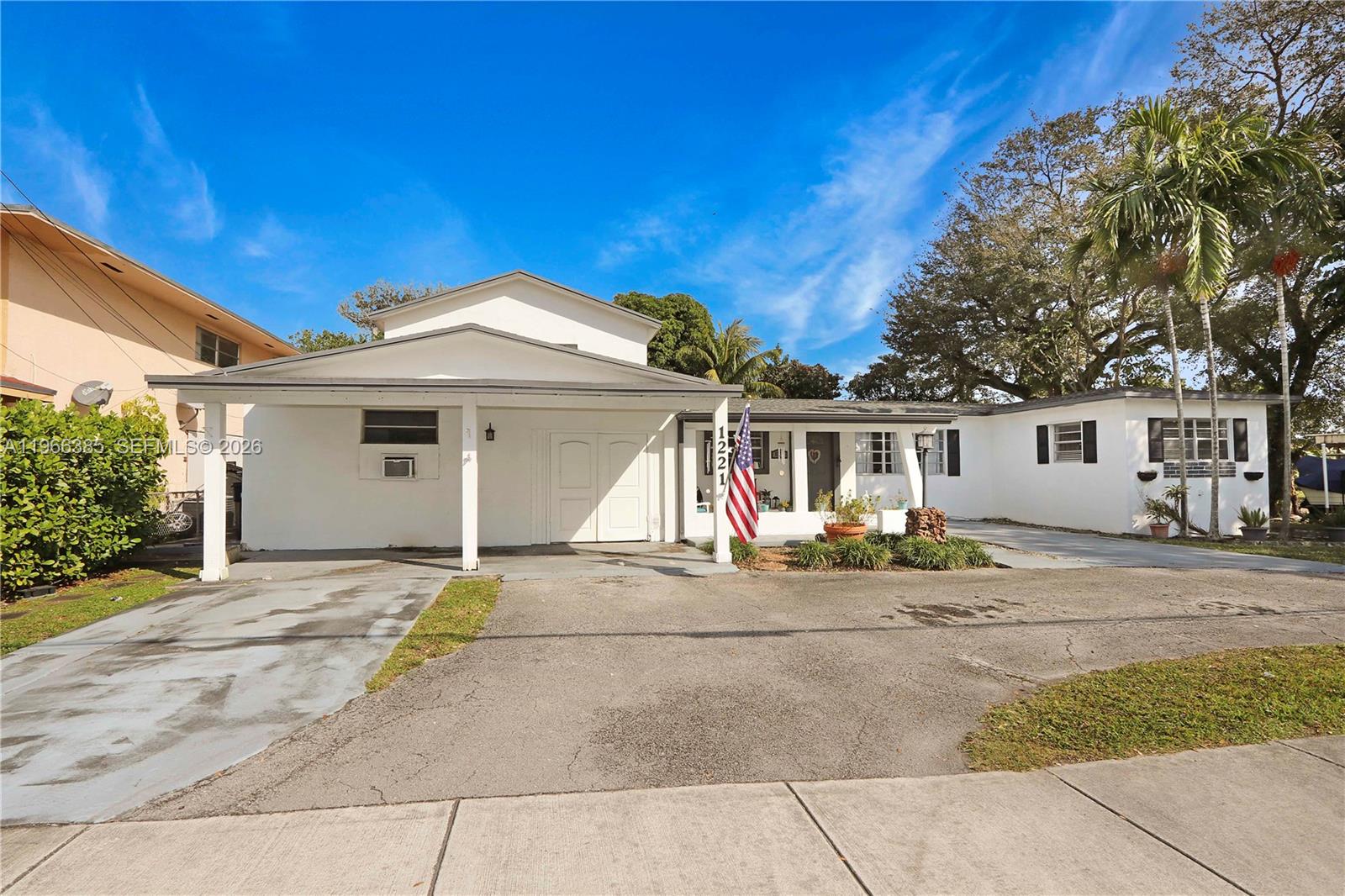 a front view of a house with outdoor seating and covered with trees