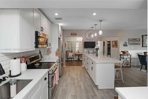 a kitchen with stainless steel appliances kitchen island granite countertop a stove and a white cabinets