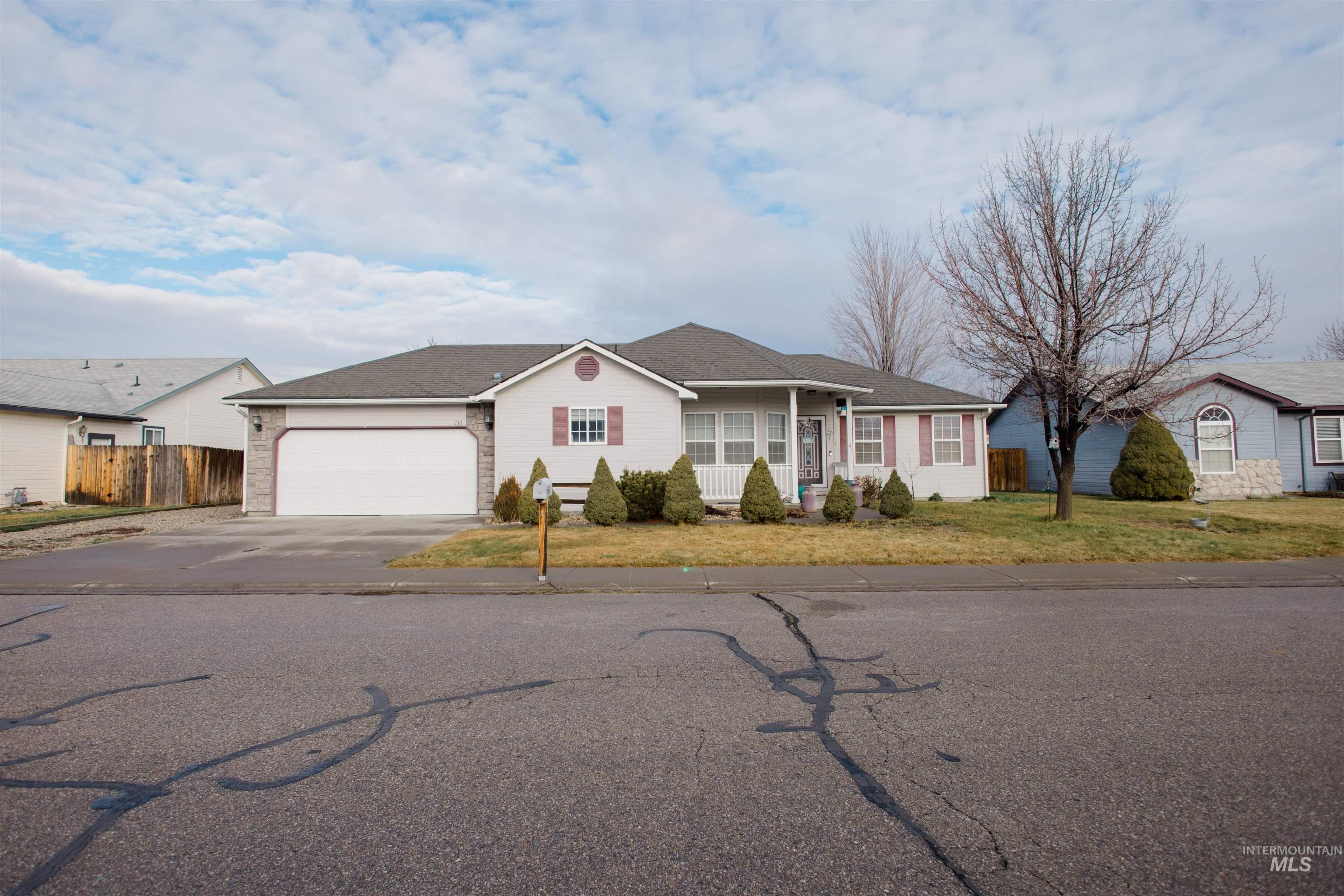 Single story home with concrete driveway, covered porch, an attached garage, and a residential view