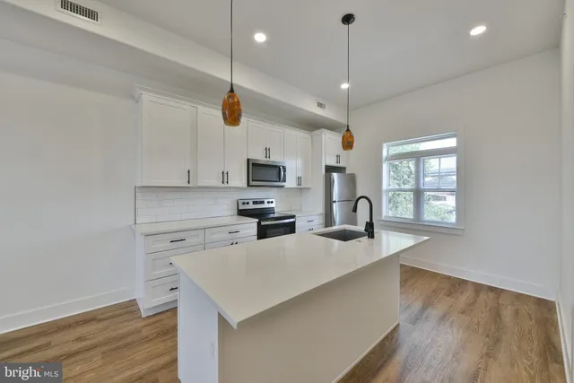 a kitchen with kitchen island a counter space a sink appliances and cabinets