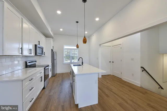 a large kitchen with kitchen island a stove a sink a refrigerator and wooden floor