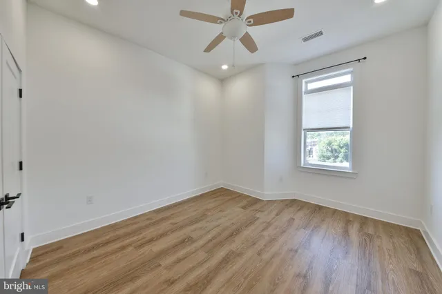 an empty room with a window and a ceiling fan