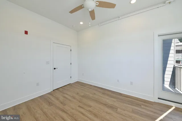 an empty room with wooden floor fan and windows