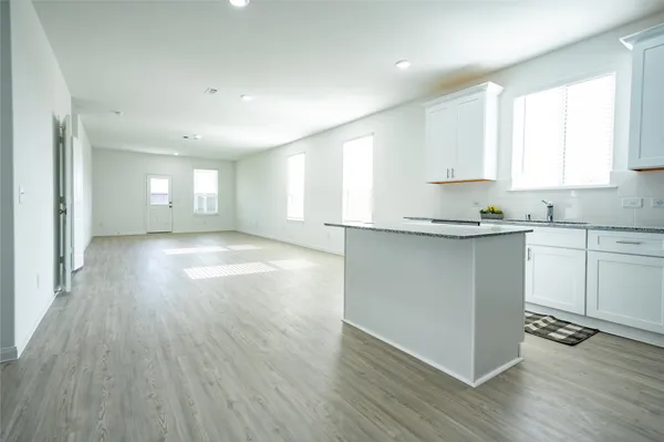 a kitchen with stainless steel appliances granite countertop a sink a stove a refrigerator and wooden floor