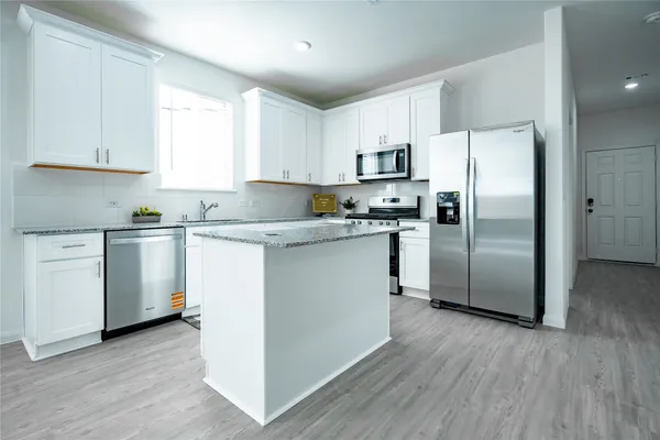 a kitchen with stainless steel appliances granite countertop a refrigerator a sink a stove a microwave and white cabinets