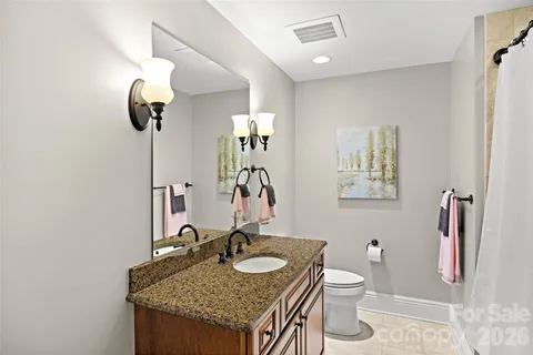 a bathroom with a granite countertop sink a toilet and mirror