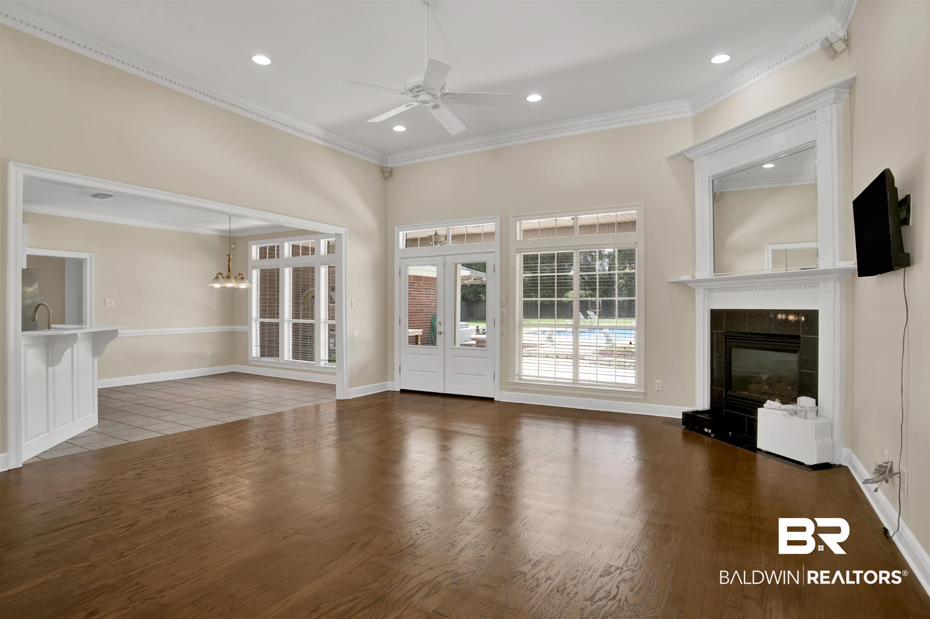 8847 Dawes Lake Road South Mobile, AL 36619 - Photo 4 of 47 Spacious living area featuring rich wood-finish flooring, a white mantel fireplace with a dark-tiled surround, and a ceiling fan