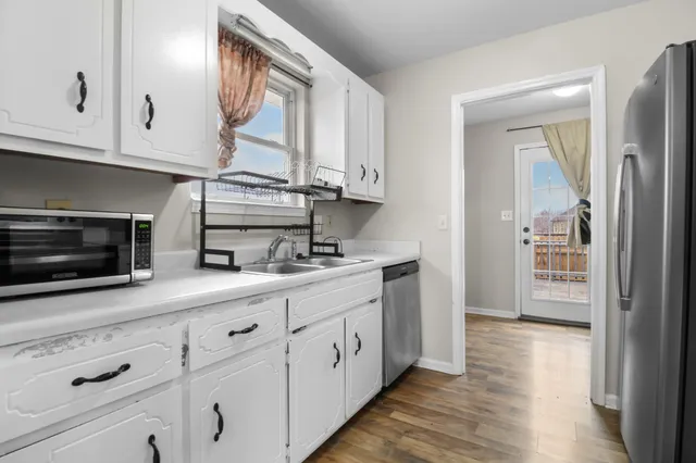 a kitchen with stainless steel appliances white cabinets and a wooden floor