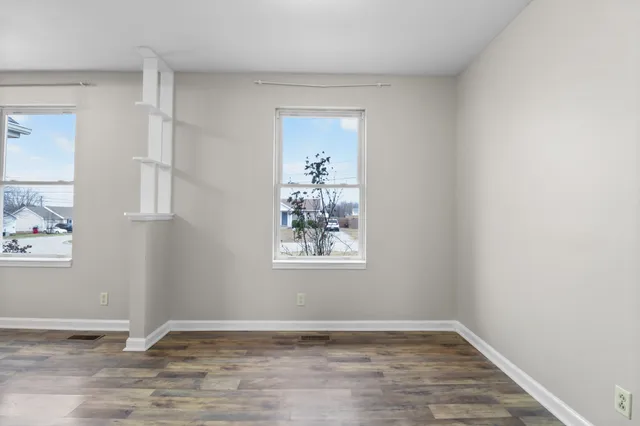 a view of an empty room with window and wooden floor