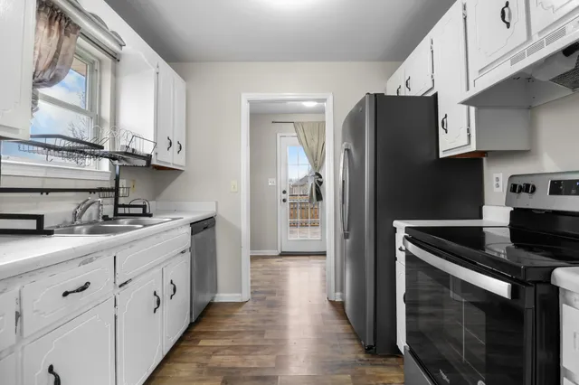 a kitchen with stainless steel appliances granite countertop white cabinets a sink a stove a refrigerator and a microwave