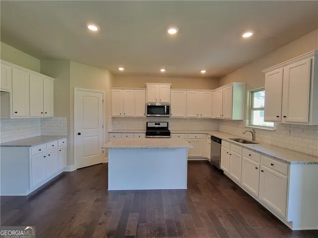 a large kitchen with cabinets wooden floor and stainless steel appliances