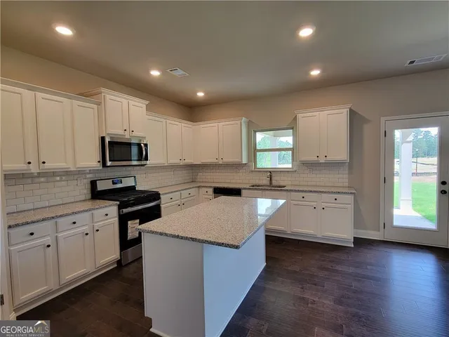 a kitchen with granite countertop white cabinets and white appliances