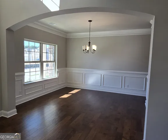 an empty room with wooden floor chandelier and windows