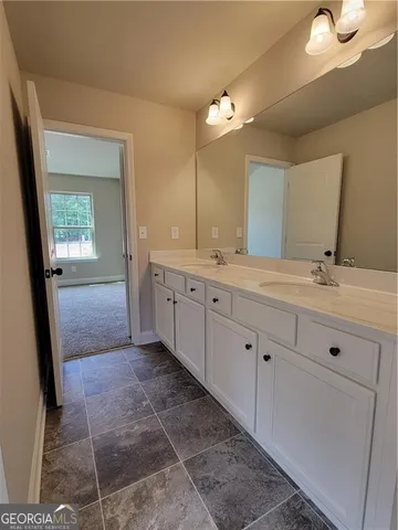 a spacious bathroom with a double vanity sink a mirror and a shower