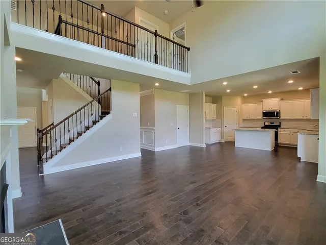 a view of a hallway with wooden floor and a kitchen