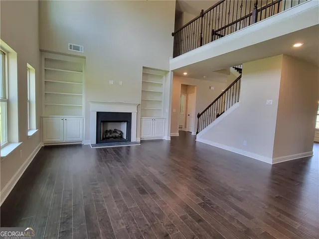 a view of an empty room with wooden floor fireplace and a window