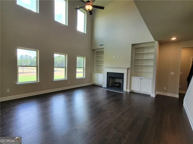 an empty room with wooden floor fireplace and windows
