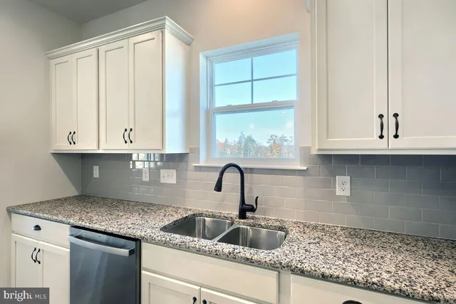 a kitchen with granite countertop a sink and white cabinets