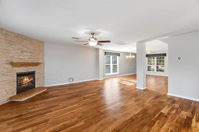 a view of an empty room with wooden floor fireplace and a window