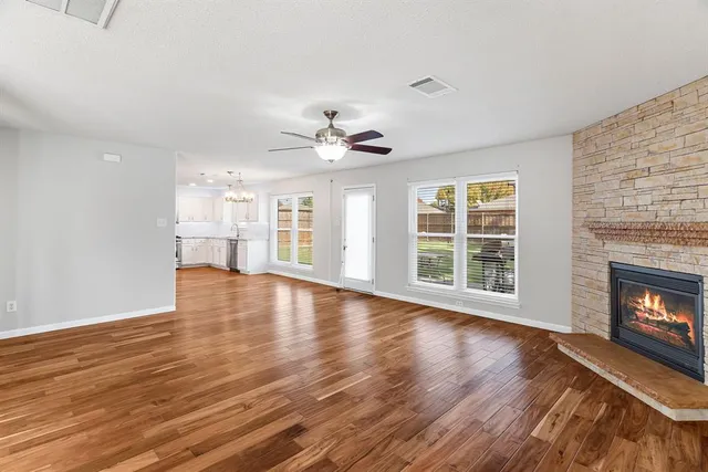 a view of an empty room with wooden floor and a fireplace