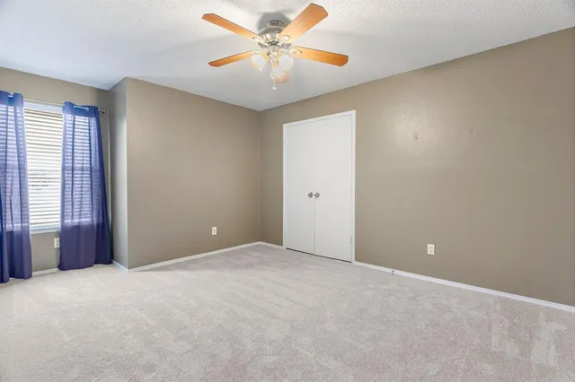 an empty room with windows and fan