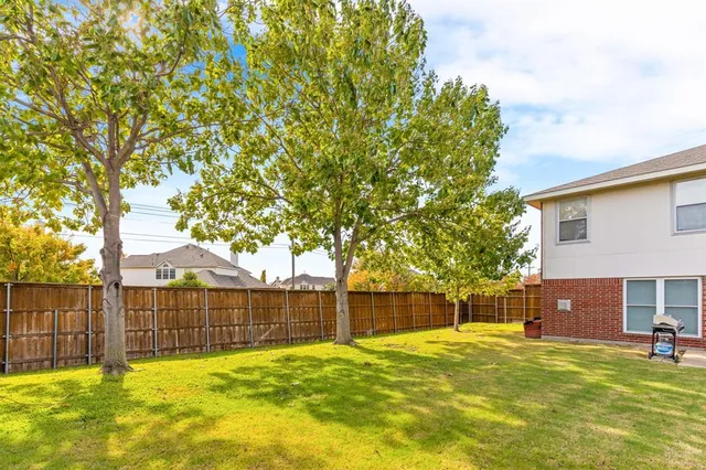 a view of a backyard with wooden fence and a large tree