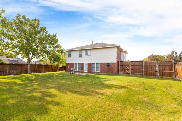 a view of a house with a yard and a large tree