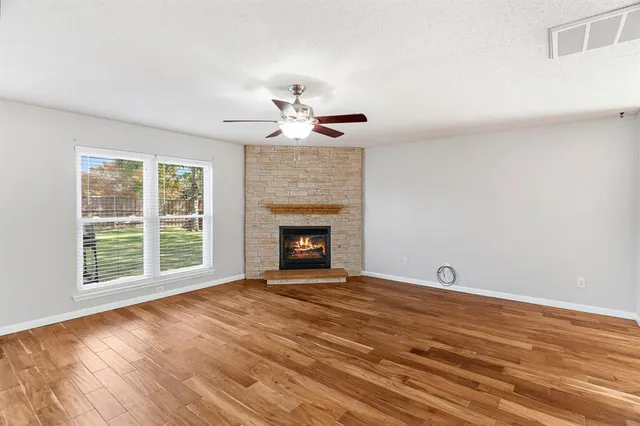 a view of an empty room with a window and fireplace