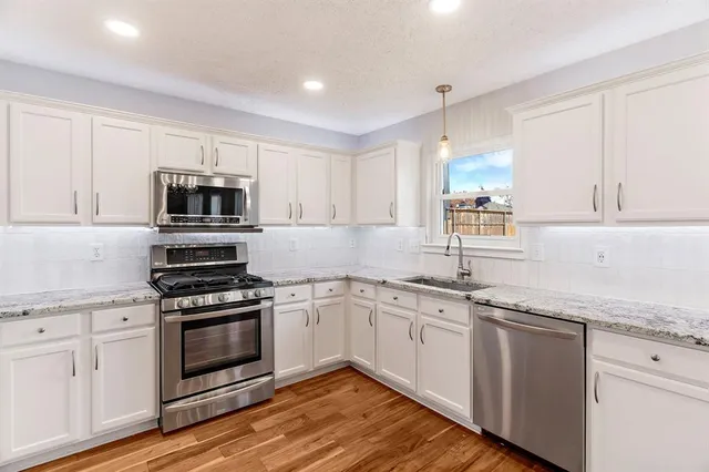 a kitchen with granite countertop white cabinets and white appliances