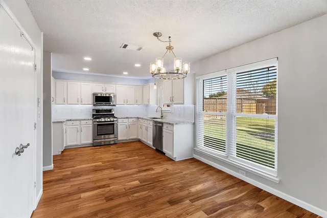 a kitchen with granite countertop a stove a sink and a refrigerator