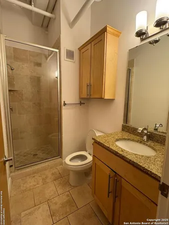 a bathroom with a granite countertop sink toilet and shower