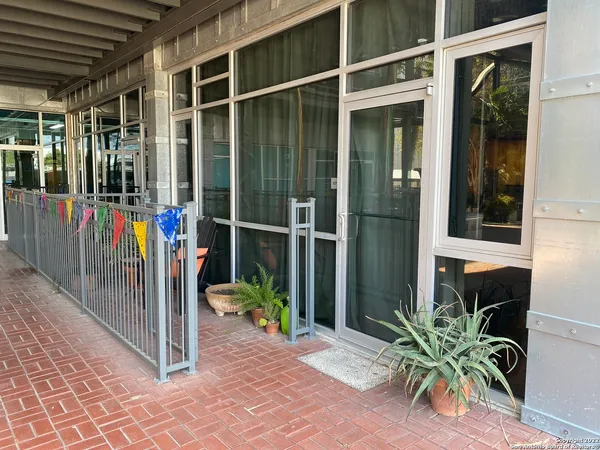 a view of a balcony with potted plants and floor to ceiling window