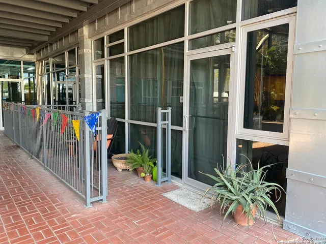 a view of a balcony with potted plants and floor to ceiling window