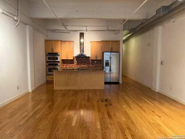 a kitchen with stainless steel appliances wooden floors and wooden cabinets