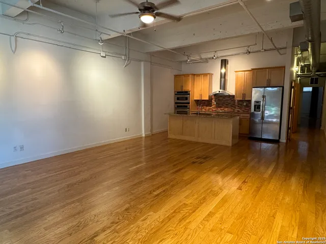 a kitchen with stainless steel appliances wooden floor and living room view