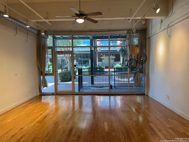 a view of empty room with wooden floor and fan