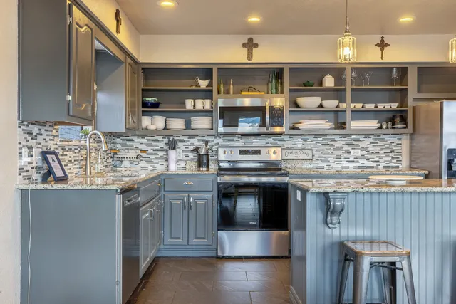 a kitchen with stainless steel appliances granite countertop a stove a sink and a microwave