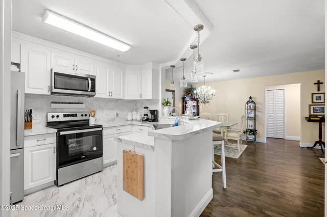 a kitchen with stainless steel appliances granite countertop a sink a stove a refrigerator and white cabinets