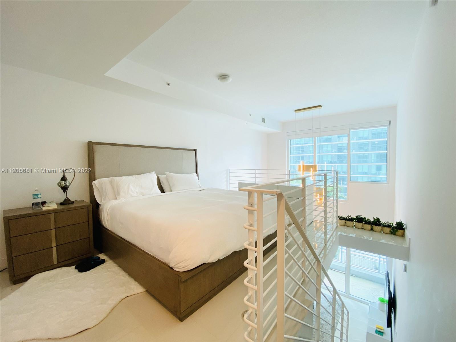60 Southwest 13th Street, Unit 1412 Miami, FL 33130 - Photo 20 of 39 a bed room with a bed and a lamp